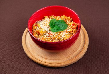 Çin pilavı susam tohumlu ve nane şekerli. Kahverengi arka planda, ahşap yuvarlak bir tahta üzerinde kırmızı bir tabakta.