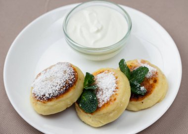 Naneli ve ekşi kremalı krep, bej arka planda beyaz yuvarlak bir tabakta cam bir tabakta.