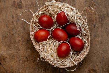 Hasır sepette kırmızı paskalya yumurtaları ahşap arka planda