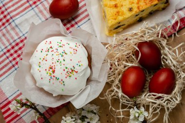 Paskalya pastası, peynir güveci ve hasır sepetin içinde tahta arka planda çiçek açan bir dalla Paskalya yumurtaları.