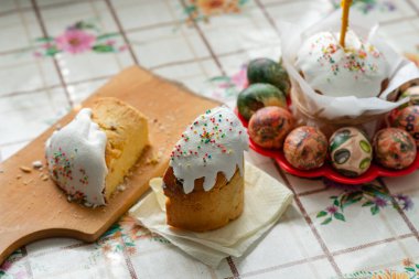 Paskalya pastası. Parşömen kağıdında mum ve kırmızı bir tabakta paskalya yumurtası. Masa örtüsü.