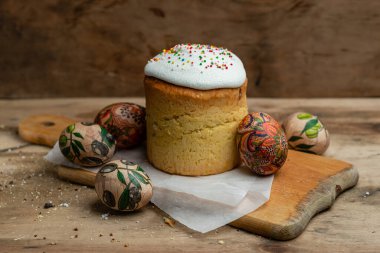 Paskalya pastası, ve parşömen kağıdındaki Paskalya yumurtaları ahşap bir arka plandaki tahta tahta üzerinde.