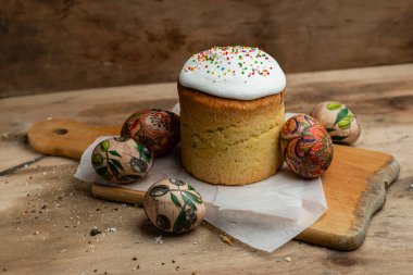 Paskalya pastası, ve parşömen kağıdındaki Paskalya yumurtaları ahşap bir arka plandaki tahta tahta üzerinde.