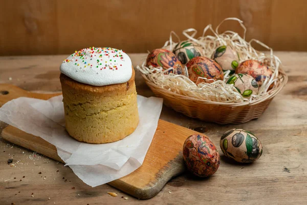 Easter cake, and Easter eggs in a wicker basket with a flowering branch on a wooden background