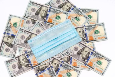Beyaz arka planda 100 dolarlık banknotlarda mavi tıbbi maske.