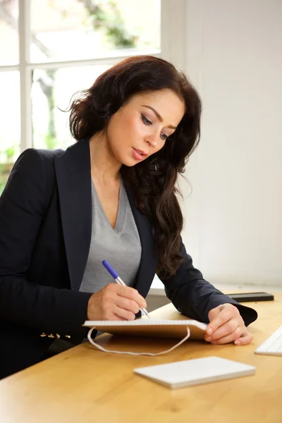 Mujer de negocios sentada en el escritorio escribiendo notas —  Fotos de Stock