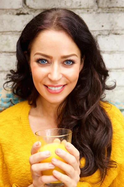 Улыбающаяся женщина держит стакан апельсинового сока — стоковое фото