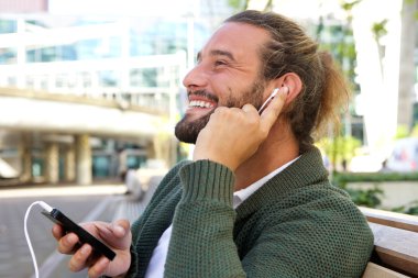 Parmağını kulağına müzik ile gülümseyen adam