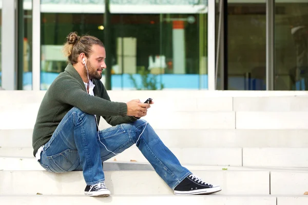 Ung man som sitter på stegen som lyssnar på musik — Stockfoto