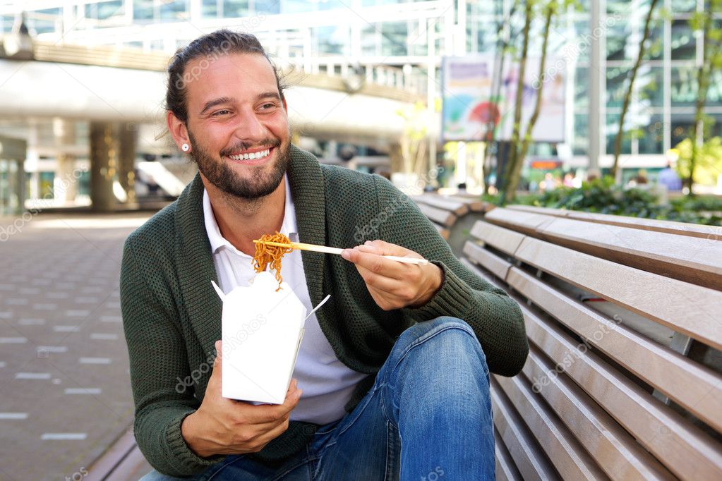 Smiling man eating chinese take away food