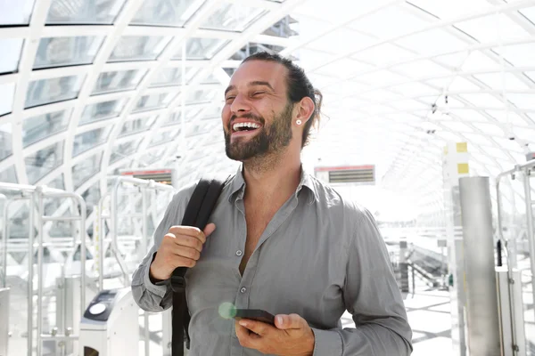 Smiling man holding cell phone in station — Stock Photo, Image