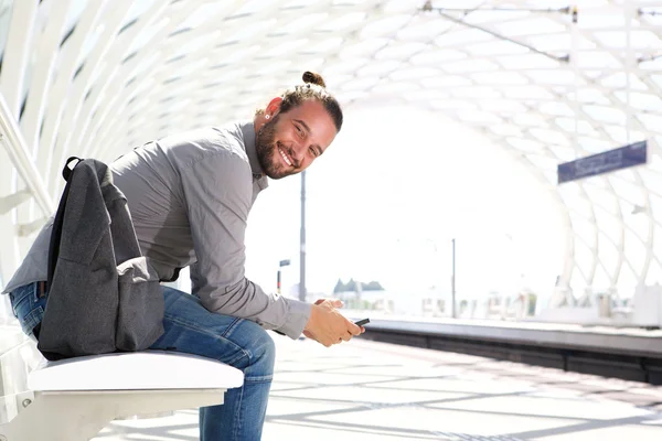 Улыбающийся мужчина с мобильным телефоном и рюкзаком — стоковое фото