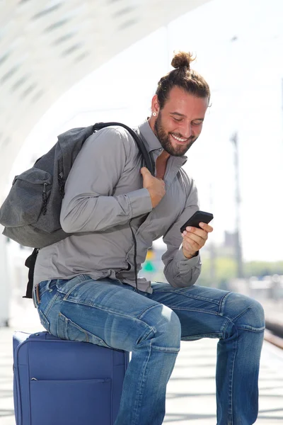Homme assis sur une valise regardant le téléphone mobile — Photo