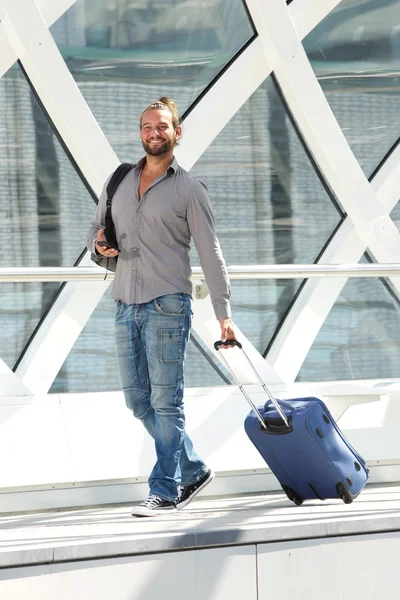 Улыбающийся путешественник ходит с чемоданом — стоковое фото