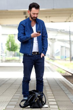 Tren istasyonunda cep telefonu kullanan adam