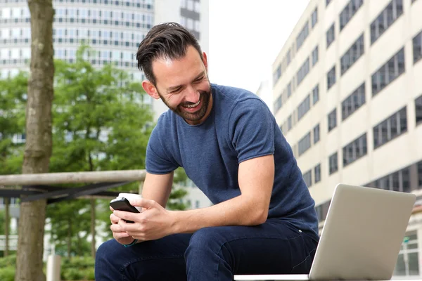 Zralý muž sedí venku při pohledu na notebook — Stock fotografie