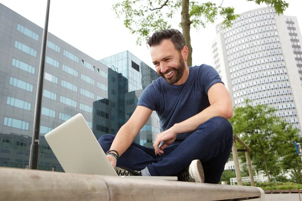 Happy ώριμος άνδρας κάθεται σε εξωτερικούς χώρους και να χρησιμοποιούν φορητό υπολογιστή — Φωτογραφία Αρχείου