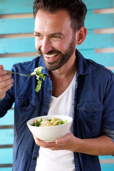 Зрелый мужчина ест салат и улыбается. — стоковое фото