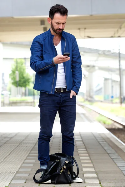 Uomo che utilizza il telefono cellulare alla stazione ferroviaria — Foto Stock