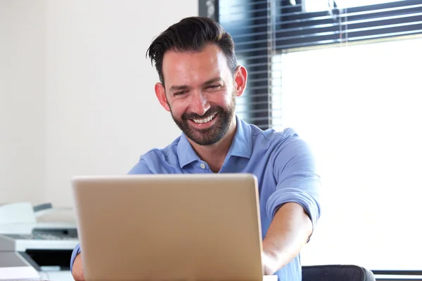 Glad mogen man sitter vid sitt skrivbord — Stockfoto