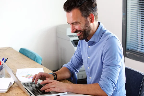 Lachende rijpe zakenman die op laptop werkt — Stockfoto