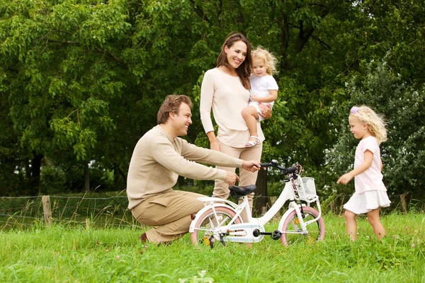 Glückliche Familie im Park mit Fahrrad — Stockfoto