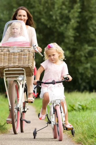 Woman with girls riding bicycles — Stockfoto