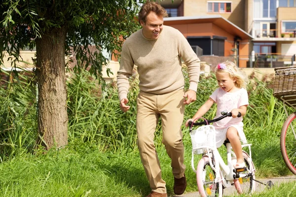 Отец учит ее дочь велоспорту — стоковое фото