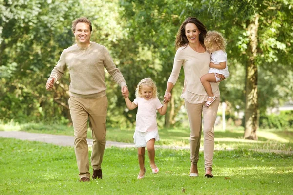 Heureuse famille de quatre personnes marchant dans le parc — Photo