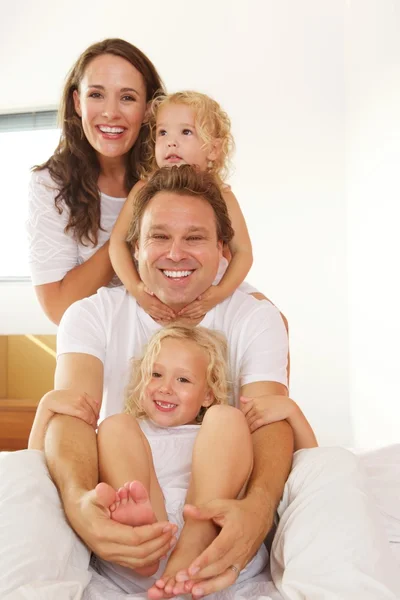 Familia alegre en la cama en casa — Foto de Stock
