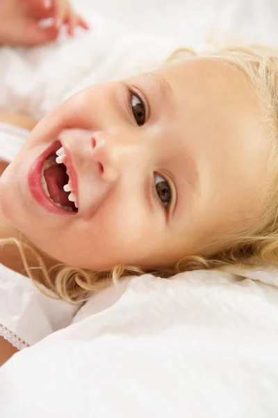 Cheerful girl lying on bed and smiling — ストック写真