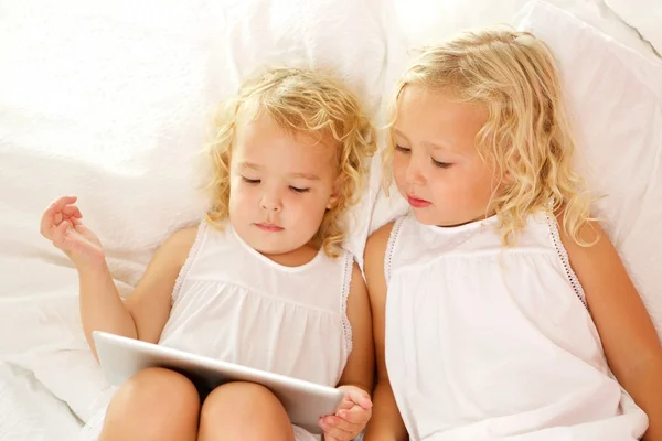 Meninas usando tablet digital na cama — Fotografia de Stock