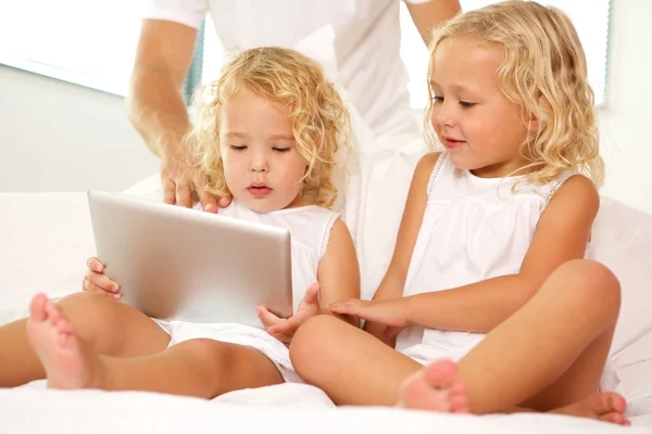 Girls sitting on bed with tablet — Stock Photo, Image