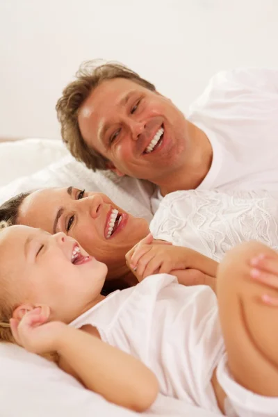 Famiglia sorridente sdraiata sul letto a casa — Foto Stock