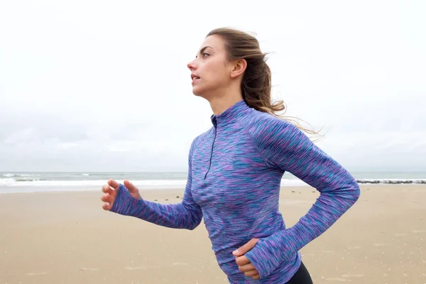 Athletic woman running of beach — ストック写真