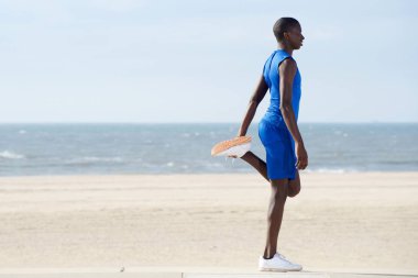 Kumsalda egzersiz yapan bir adam.