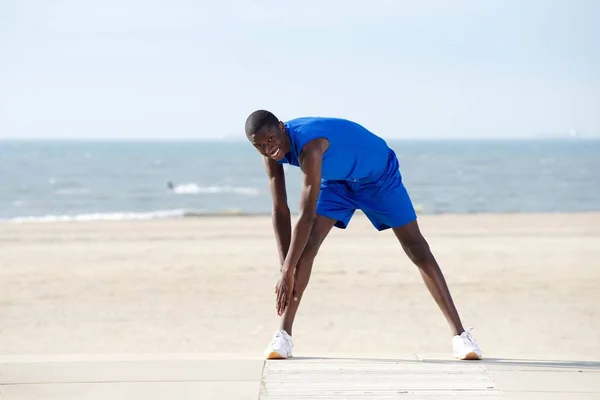 Африканский мужчина растягивается на пляже — стоковое фото