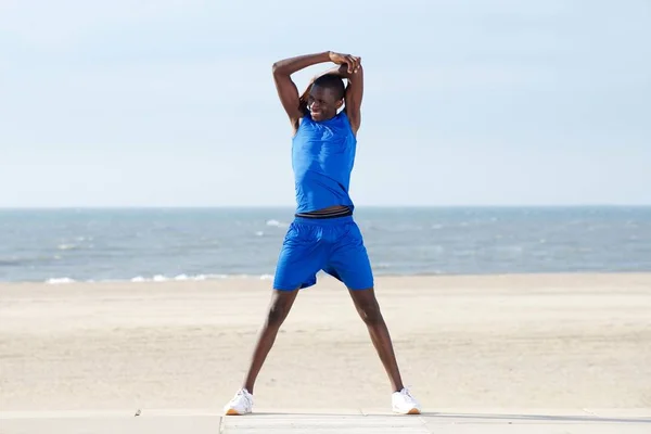 Африканский мужчина растягивается на пляже — стоковое фото