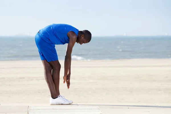 Uomo africano che si estende sulla spiaggia — Foto Stock