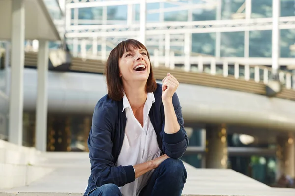 Mujer riendo sentada afuera — Foto de Stock