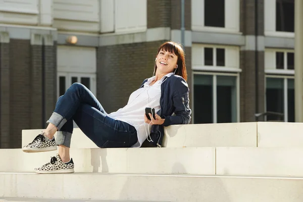 Kvinnan sitter på stegen och lyssnar musik — Stockfoto