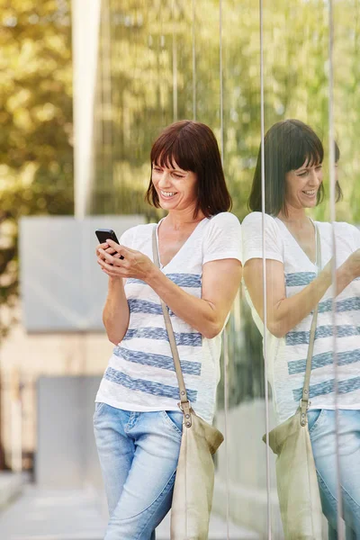 Frau stützt sich mit Handy auf Reflexion — Stockfoto
