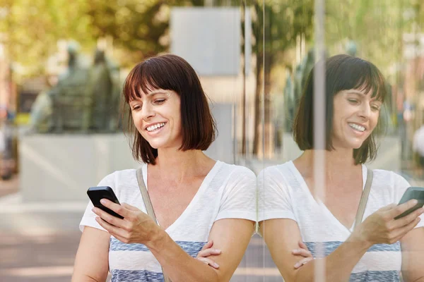 Mujer apoyada en la reflexión usando el teléfono — Foto de Stock