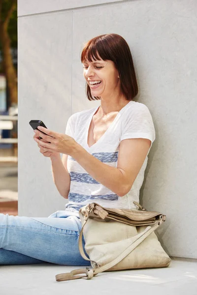 Vrouw zittend op de grond met telefoon — Stockfoto