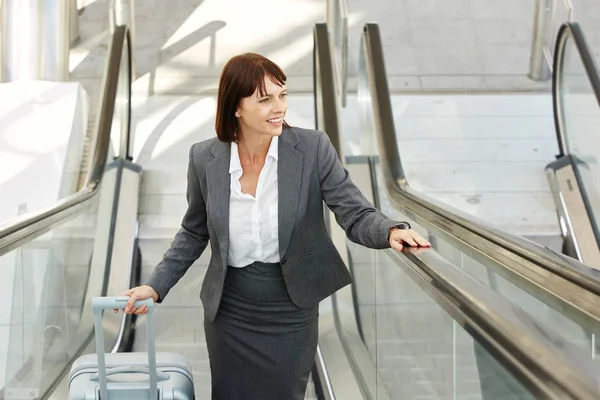 Kvinna med resväska står på rulltrappan — Stockfoto