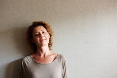 Duvara yaslanmış kıvırcık saçlı kadın