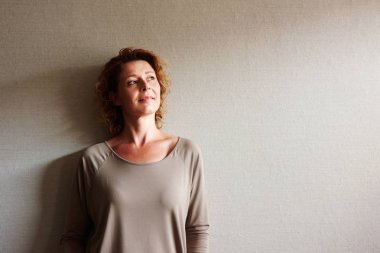 Duvara yaslanmış kıvırcık saçlı kadın