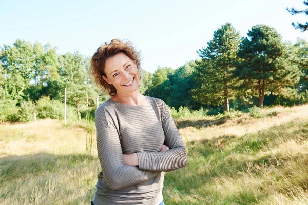 Frau steht mit verschränkten Armen im Park — Stockfoto