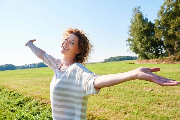 Woman standing outside with arms raised — Stock Photo, Image