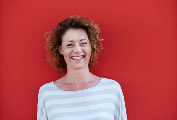 Vrouw met krullend haar tegen muur — Stockfoto